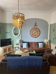 a living room with a couch and a clock on the wall at Beach House in Lytham St Annes