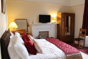 
a bedroom with a bed, a dresser and a television at Brackness House Luxury B&B in Anstruther
