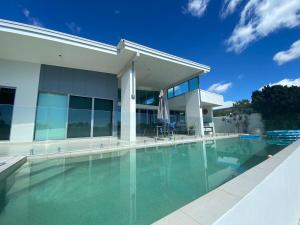 a swimming pool in front of a house at Lakefront Luxury Golf & Beach in Pelican Waters