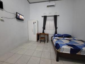 a bedroom with a bed and a table and a television at Alia Corner Homestay in Mandiraja +19 photos