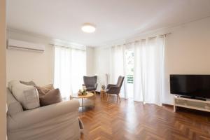 a living room with a couch and a flat screen tv at Seaside Elegance Brand New 2BD Luxury Stay in Athens
