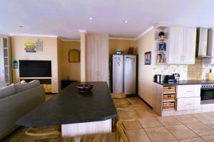 cocina y sala de estar con mesa y nevera en Happy Tides Main House, en Struisbaai