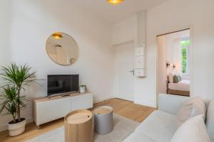 een witte woonkamer met een tv en een spiegel bij Appartement T2 proche tramway et commodités in Tourcoing