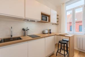 een keuken met witte kasten, een gootsteen en een raam bij Appartement T2 proche tramway et commodités in Tourcoing