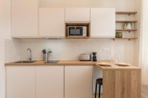 een keuken met witte kasten en een aanrecht met een magnetron bij Appartement T2 proche tramway et commodités in Tourcoing