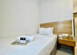 a white bed with a tray of wine bottles on it at ATAP Hotel in Kota Kinabalu