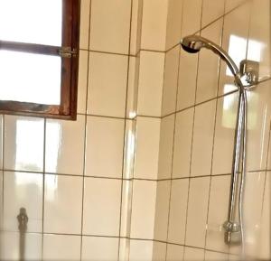 a shower head on a tiled wall in a bathroom at Casa Motel in Ziguinchor