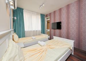 a bedroom with two beds and a tv on the wall at Luxury Apartment Saint George Beauty and Style in Sveti Vlas