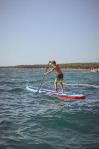 a man standing on a paddle board in the water at Camping Bi-Village - Roan in Valbandon