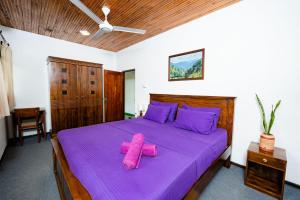 une chambre avec un lit violet avec une serviette rose dessus dans l'établissement Villa Alma, à Ahangama