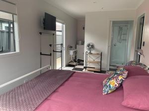 a bedroom with a large bed with a pink blanket at 1 bedroom studio with 2 E-bikes for use in Napier