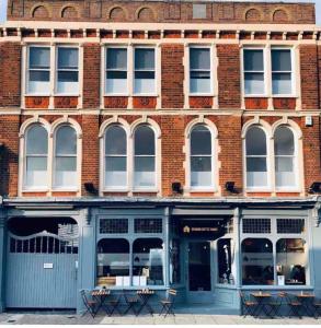 a large brick building with blue doors and windows at Ground Floor Studio Apartment in Burnham on Crouch