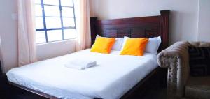a bed with orange and white pillows and a window at Essik Homes Studio 1 - Muthiga, Waiyaki Way in Nairobi +11 photos