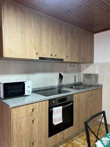 a kitchen with a microwave and a stove top oven at Casa do Cascalho in Ribeira de Pena +4 photos