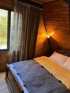 a bed in a wooden room with a window at Cottage Milu კოტეჯი მილუ in Kutaisi
