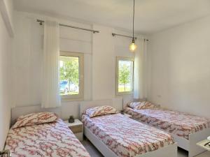two beds in a room with two windows at Perla Holiday Homes 246 in Lalzit Bay