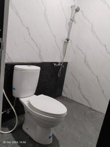 a white toilet in a bathroom with a hose at Majid's Homestay Solo in Kartosuro +19 photos