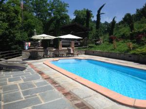 una piscina con sedie e ombrelloni in un cortile di Poderi S Luca ad Alba