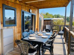 a table on the deck of a house with chairs at Chalet 3 chambres Bassin Arcachon - Camping- Parc aquatique in Gujan-Mestras