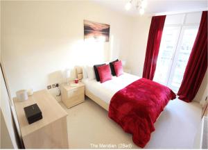 a bedroom with a bed with a red blanket and a desk at Reading Modern Two Bedroom Apartment in Reading +2 photos