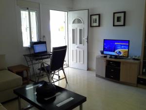 ein Wohnzimmer mit einem Sofa, einem TV und einem Tisch in der Unterkunft Apartment 241 in Gran Alacant