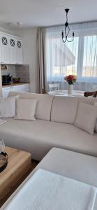 a living room with a white couch and a kitchen at Apartmán Ellis in Podhájska