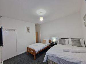 a white room with two beds and a tv at Nice Living Serviced Accommodations 12 in Coventry