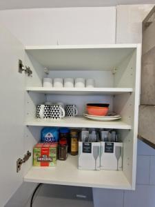 a white pantry with cups and dishes on shelves at Nice Living Serviced Accommodations 12 in Coventry