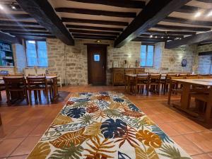 a dining room with a colorful rug on the floor at Gîte et Hostel Le Ty Bihui in Bieuzy-les Eaux