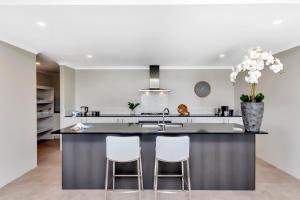 a kitchen with a large island with two stools at Oceanfront Retreat With Stunning Marina Views in Mandurah