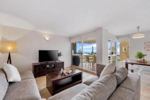 a living room with a couch and a flat screen tv at Headlands 10 Two Bedroom Beachside Apartment with Magical Ocean Views Great Value for Money in Alexandra Headland