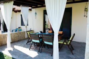 a table and chairs on a patio with white curtains at Maisonette with sea and mountain view !!! in Kriopigi