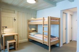 马蒂尼威尔Martigny Youth Hostel的一间卧室配有双层床、桌子和书桌