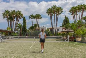a woman is standing on a tennis court at Casa Munich in Ses Salines +56 photos