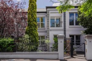 ein weißes Haus mit einem Tor und Bäumen in der Unterkunft Adelaide Oval Townhouse - Walk to the AFL & CBD in North Adelaide