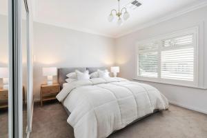 ein weißes Schlafzimmer mit einem großen Bett und einem Fenster in der Unterkunft Adelaide Oval Townhouse - Walk to the AFL & CBD in North Adelaide