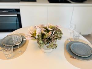 a table with plates and a vase with flowers on it at RAUM2GO - NO3 stylisches studio KURPARK & CITY in Wiesbaden