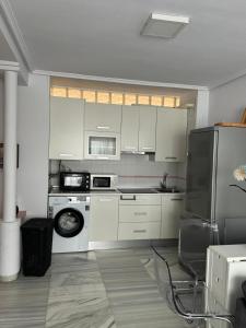 a kitchen with white cabinets and a black refrigerator at Acogedor al lado de el mar in Roquetas de Mar