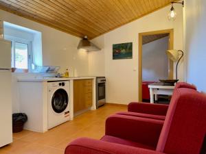 a kitchen with a washing machine and two red chairs at Casas do Montinho in Melides