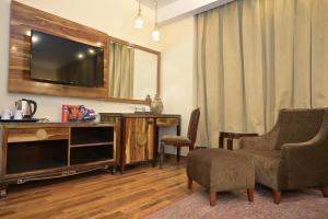 a living room with a flat screen tv and two chairs at HK Clarks Inn, Amritsar in Amritsar