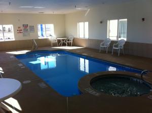 una piscina en una habitación de hotel con mesa y sillas en Lea County Inn, en Hobbs