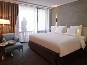 a bedroom with a large white bed and a chair at Pullman Paris Tour Eiffel in Paris