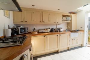 a kitchen with white cabinets and a stove top oven at Number 60 Donkey Lane in Burton Bradstock