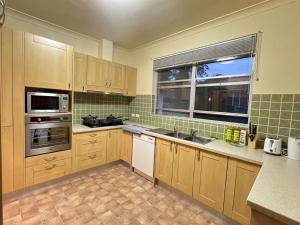 a kitchen with wooden cabinets and a sink and a window at 30 Room in Epping