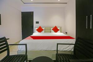 a bedroom with a bed with red pillows and two chairs at Super Hotel O Botcha Convection in Visakhapatnam