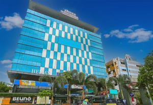 a tall glass building with trees in front of it at Super Hotel O Botcha Convection in Visakhapatnam