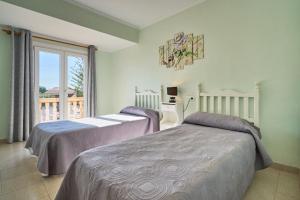 two beds in a bedroom with a balcony at Villa Tos in Sa Coma +90 photos