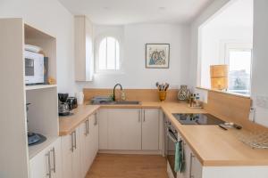 a kitchen with white cabinets and a sink and a microwave at Les Terrasses 2 in Leucate-Plage