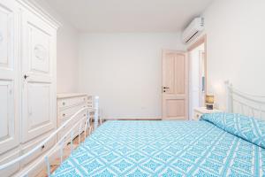 a white bedroom with a bed and a dresser at Villa Giardino in Villasimius