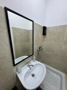 Un baño con lavabo, espejo y bañera. en Uide hotel, en Almaty